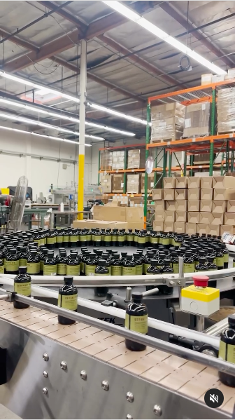 A large conveyor belt transporting multiple bottles in a production or packaging facility.