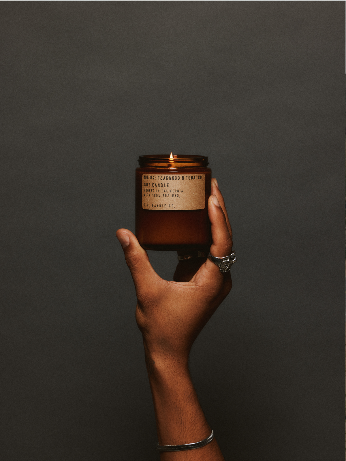 Hand holding a lit soy candle, symbolizing mindfulness, comfort, and creating a calming space for emotional reflection.