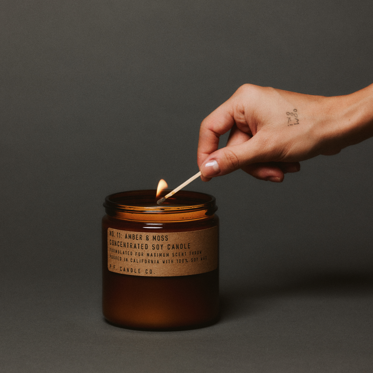 amber & moss large concentrated candle being lit up with match in hand 