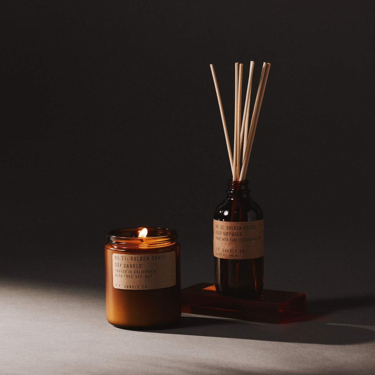 golden coast candle and reed diffuser set on a dark background