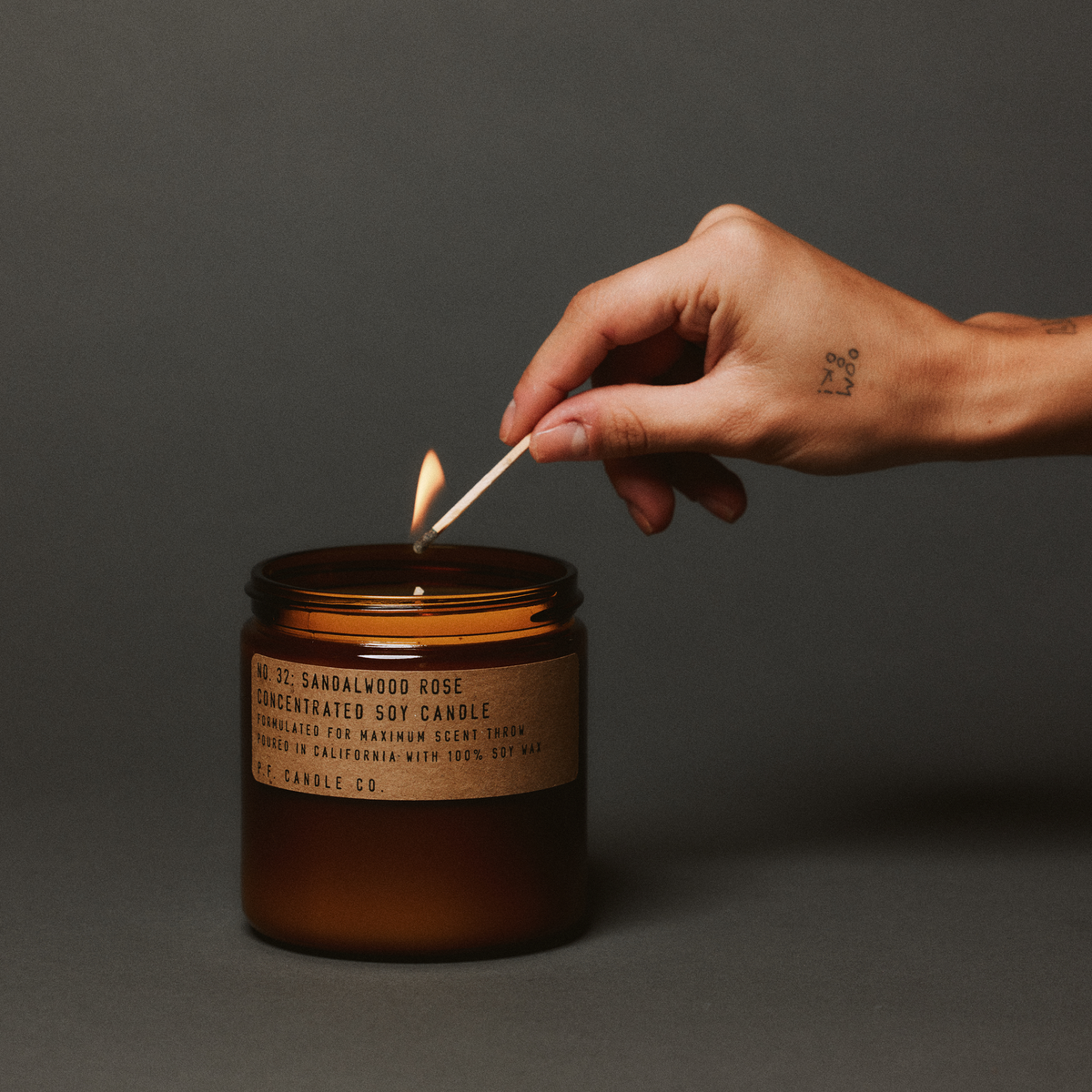 sandalwood rose large concentrated candle being lit up with match in hand 
